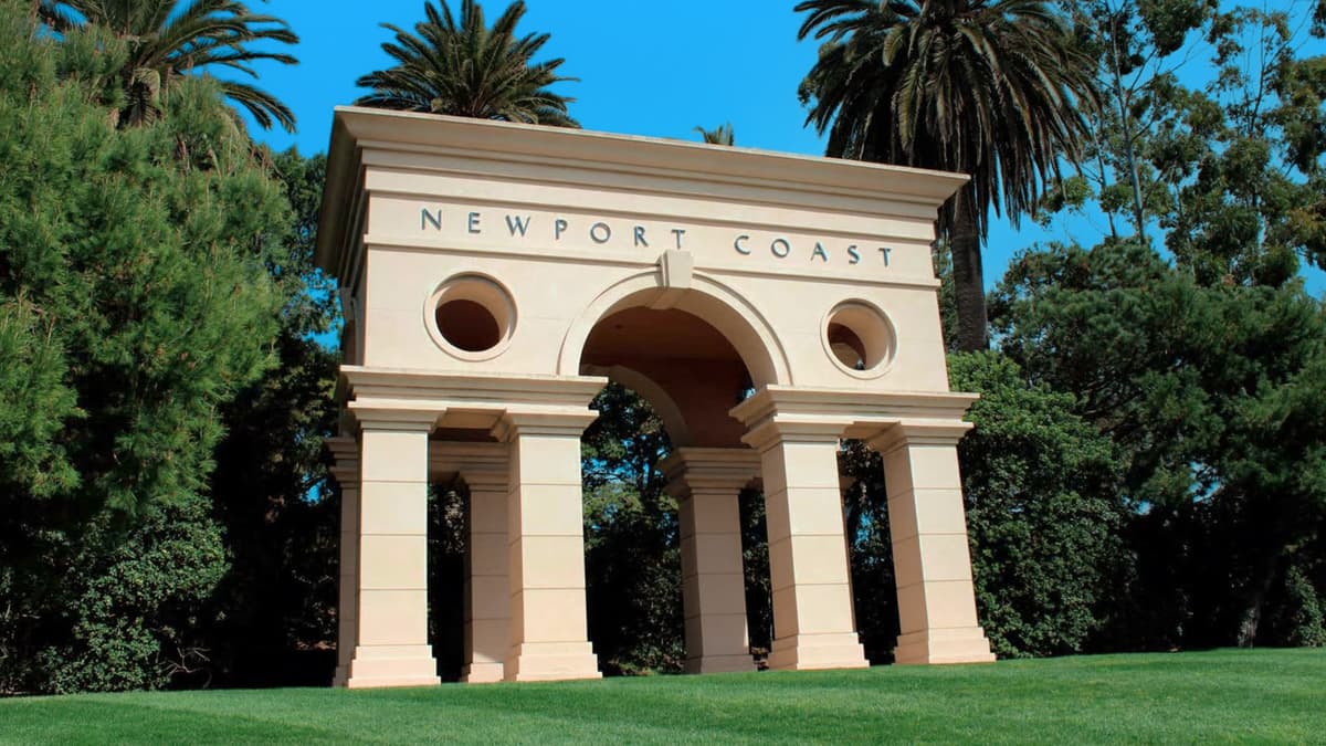 The Newport Coast monument framed by palm trees